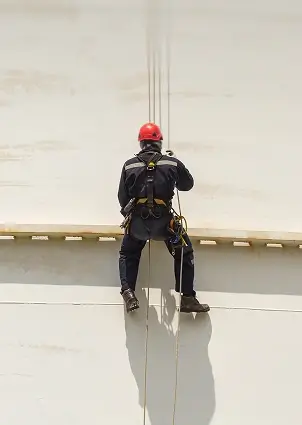 An industrial climber in an orange hard hat at work.